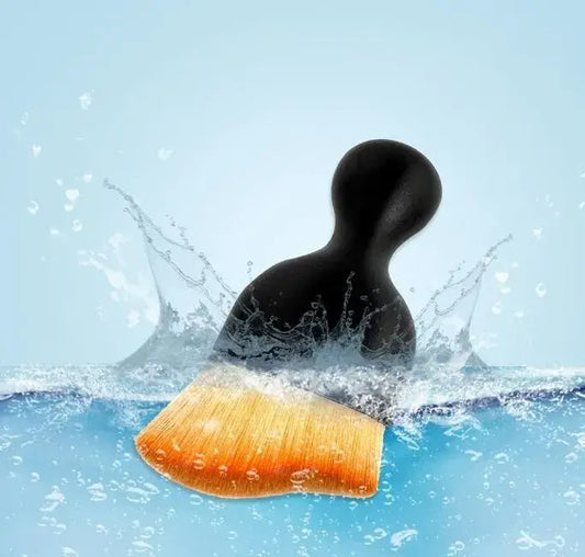 Black rubber duck with a yellow beak splashing in water on a light blue background