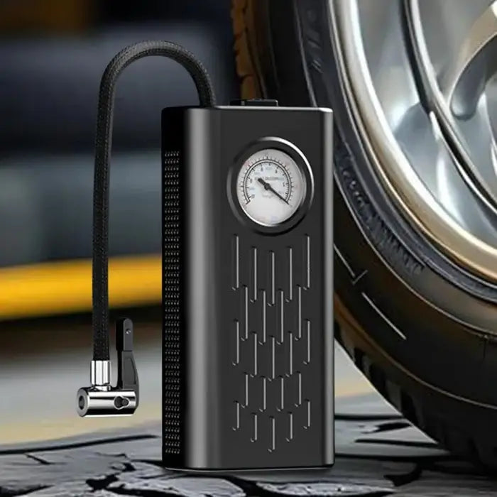 Black portable air compressor with pressure gauge next to a tire