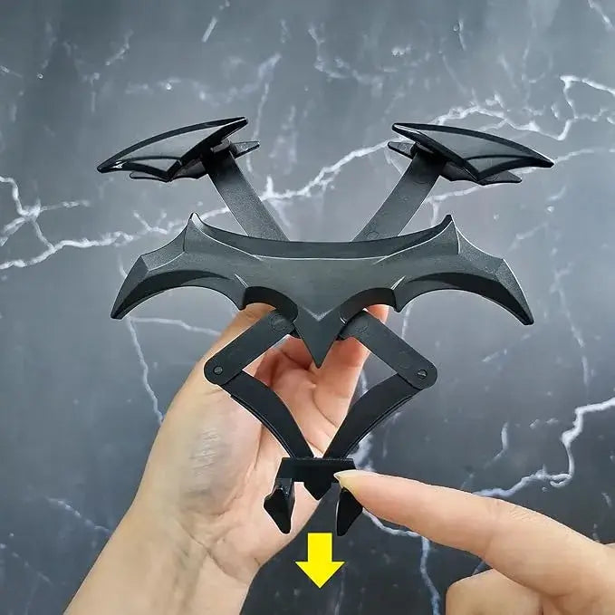 Hand holding a black three-pronged weapon against a gray marble background