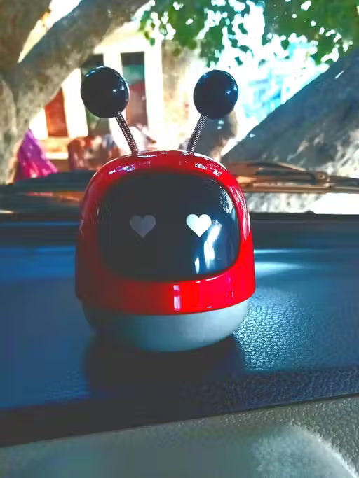 Red and white toy with heart designs on a car dashboard