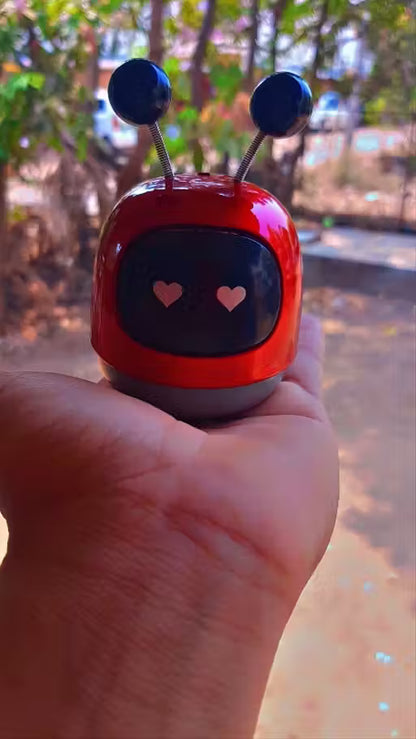 Small red robot toy held in a hand with a blurred outdoor background