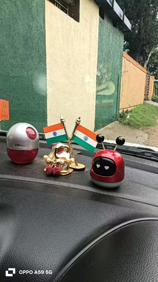 Car dashboard with decorative items including a small flag and a red and silver object.