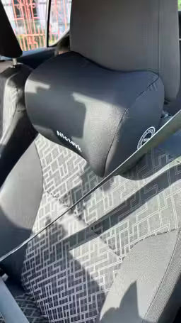 Car interior with a headrest and seat cover featuring a geometric pattern.