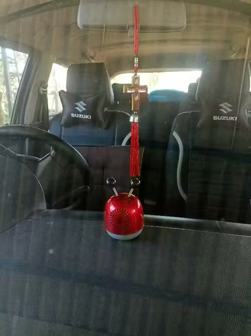 Red car hanging ornament with cross on a car seat inside a vehicle.