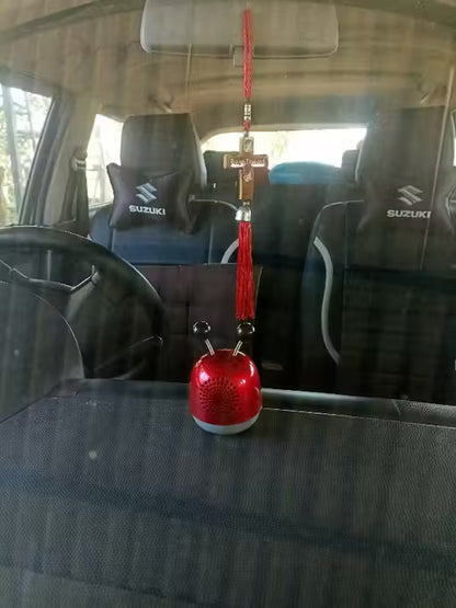 Red car hanging ornament with cross on a car seat inside a vehicle.