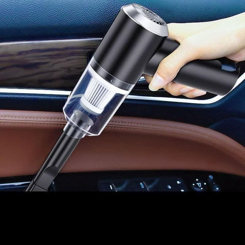 Hand holding a black car vacuum cleaner inside a vehicle.