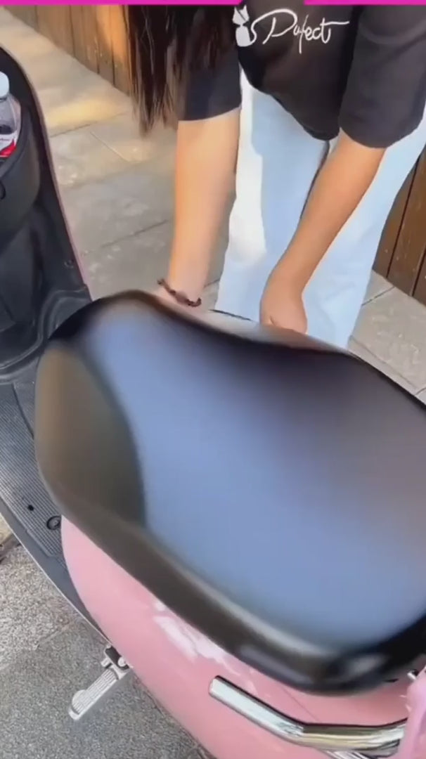 Person placing a premium waterproof bike seat cover on a pink scooter seat, showcasing its sleek design.